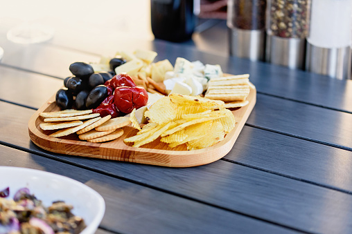 Mix of different snacks and appetizers. Street food plate with set of various kind snacks: bread spicy crackers, french fries and dip, tomatoes, delicious cheese on dark background. antipasto plate