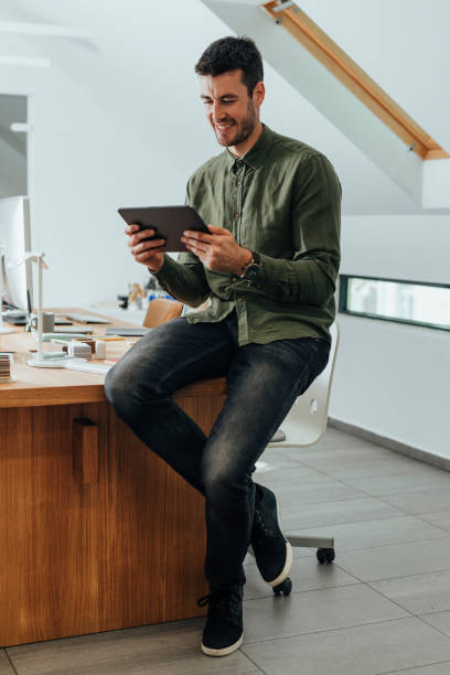 istock Smiling Businessman in a Green Shirt Using a Digital Tablet in the Office 1312953592
