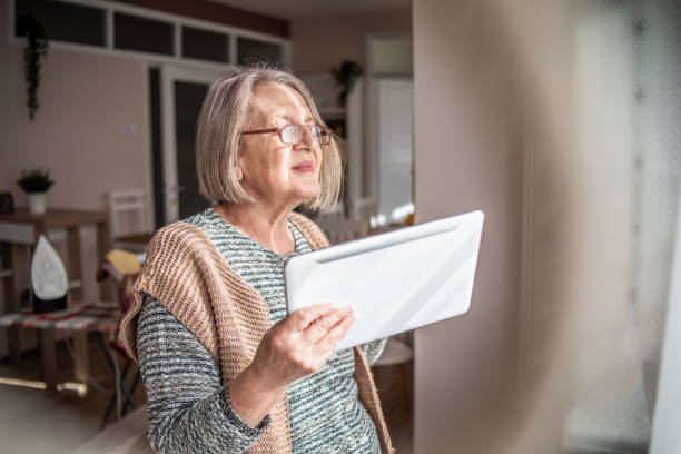istock An elderly woman reading a newspaper on a digital tablet and drinking her coffee. 1312953759