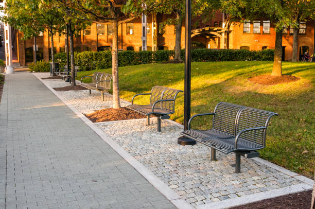 Empty stylish metal benches in a public park at sunset