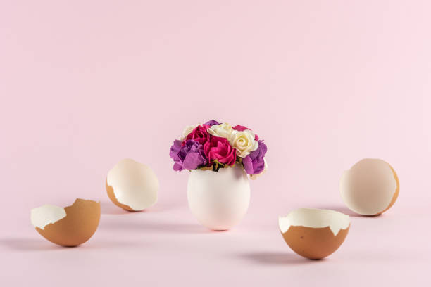 istock Spring flowers in cracked eggshell with broken Easter eggs against pastel pink background. Easter minimal concept. Creative Happy Easter or spring layout. 1312955696
