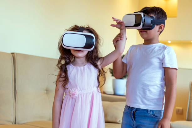 istock Excited Little Children are Using VR Goggles and Gesturing with Their Hands. 1312956893