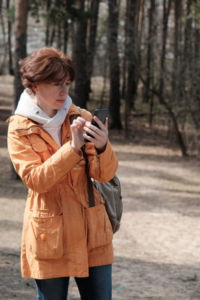 istock Mature woman is using smart phone in forest 1312958498