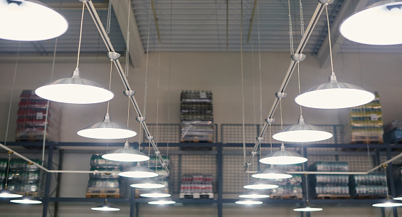 Close-up of glowing lamps in a warehouse with goods on the shelves.