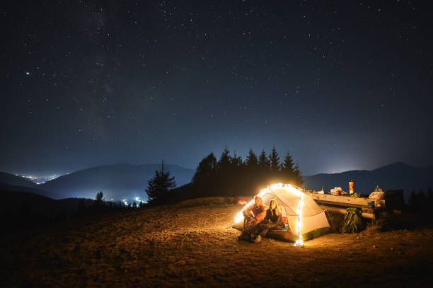 istock Hikers sitting inside camp tent and looking at night starry sky. 1312962921