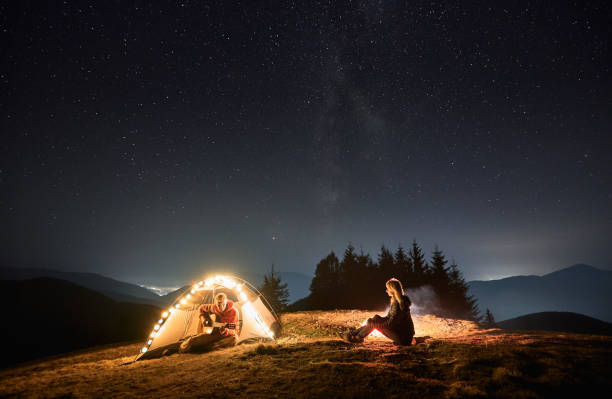 istock Loving couple spending time together in mountains under night sky. 1312962947