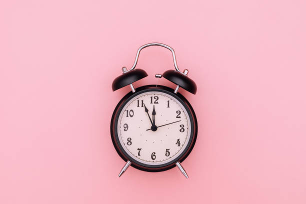 istock Black alarm clock on pink background 1312963096
