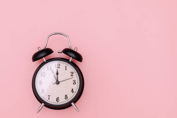 istock Black alarm clock on pink background 1312963097