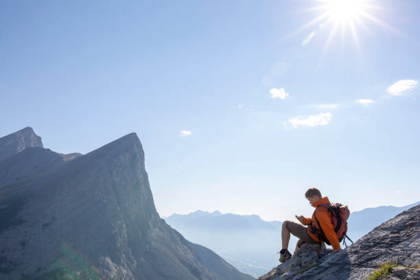 istock Young man pauses on rock ridge crest, above mountains 1312965373