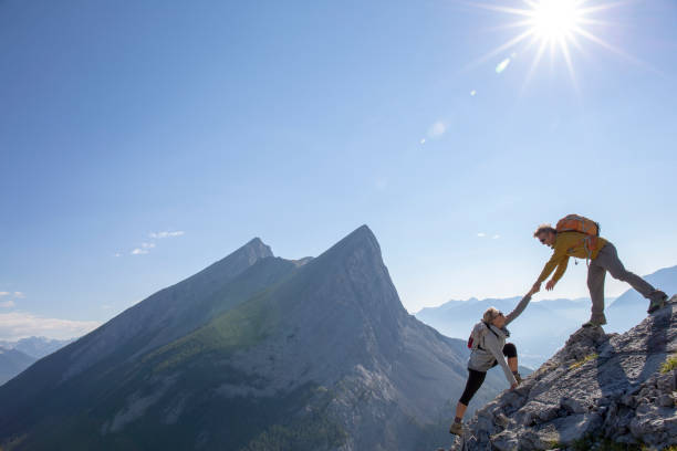 istock Hiking couple ascend rock ridge crest, above mountains 1312965398