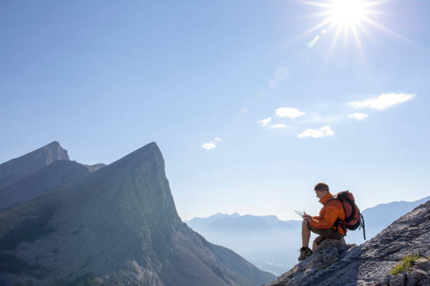 istock Young man pauses on rock ridge crest, above mountains 1312965486