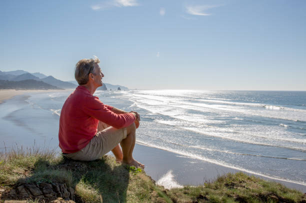 istock Mature man relaxes above beach on headland, sunrise 1312965506