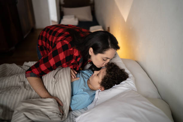 madre che mette il figlio a dormire a casa - bedtime foto e immagini stock