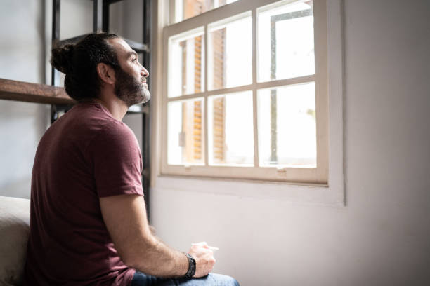 istock Man looking through the window at home 1312969207