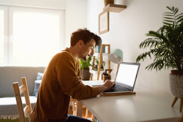 istock Happy young man using a laptop at home 1312971538