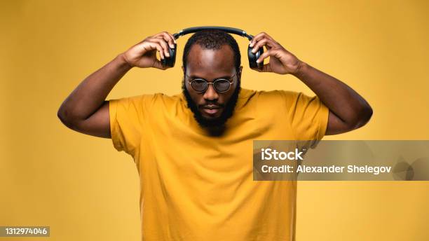 Africanamerican Ethnicity Person With Eyeglasses And Wireless Black Headphones Is Listening Music Concept For Dj Techno Pop Rap Rb Music Photography Studio Portrait On Yellow Background Stock Photo - Download Image Now