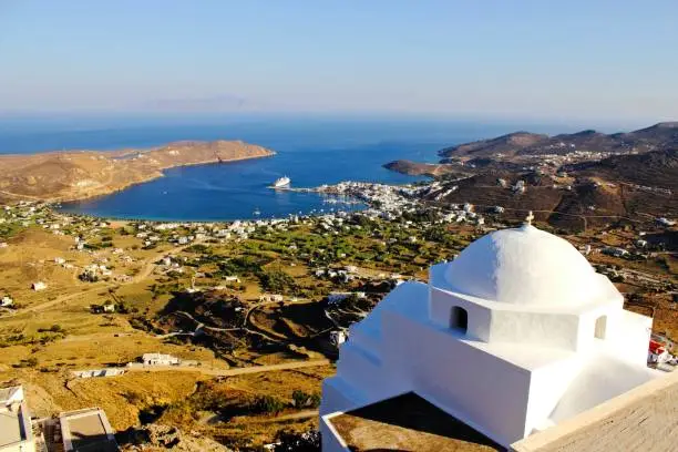 View of Christian orthodox church with Livadi, the port of Serifos island in the background. Cyclades islands, Greece.