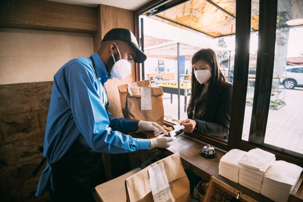 istock A masked server takes payment from a masked customer in this Covid-19 pandemic 1312980463