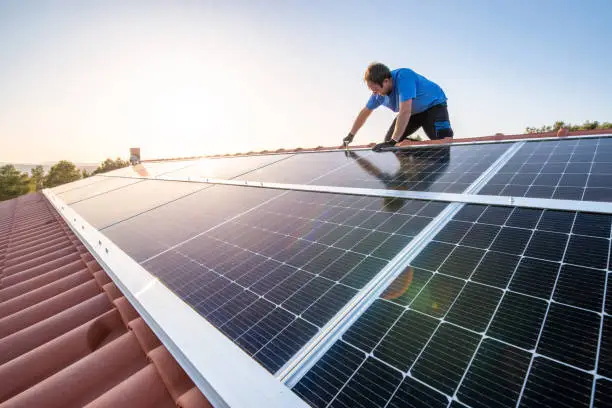 Photo of Professional worker installing solar panels on the roof of a house.
