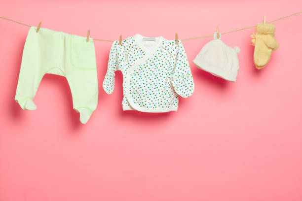 istock Baby clothes on a clothesline on pink background - Image 1312981539
