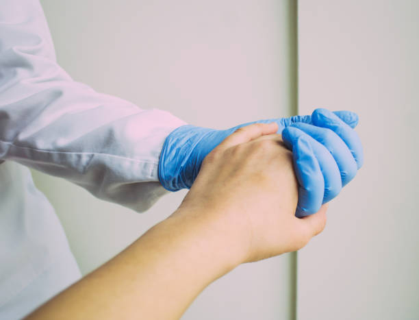 istock woman's hand holding a doctor's hand with blue glove 1312984240