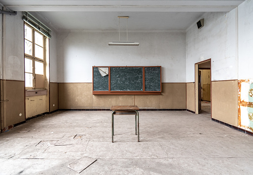 Abandoned dilapidated classroom with scribbles left on the blackboard