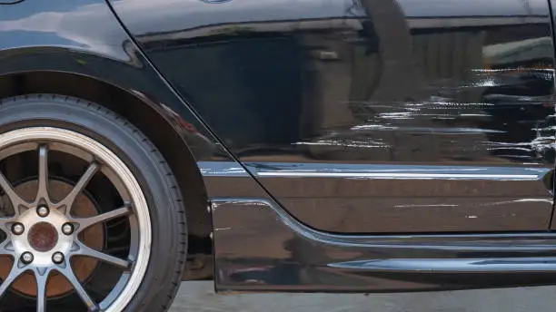 Photo of Damaged scratch on black car surface after accident