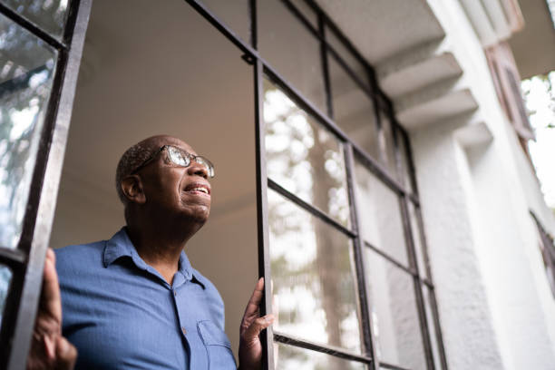 istock Senior man looking through the window at home 1312993570