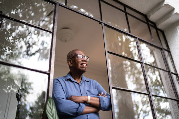 istock Senior man looking through the window at home 1312993615