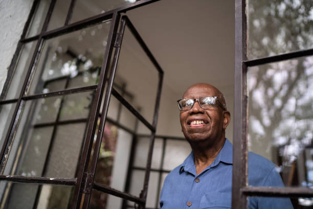 istock Senior man looking through the window at home 1312993629
