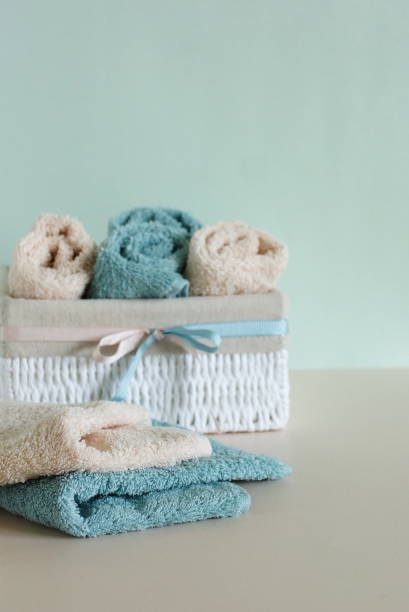 istock Stack of folded and rolled beige and green terry towels in the white basket  on beige background.Copy space.bathroom accessories backdrop. 1312994311