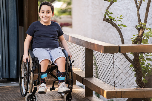 Portrait of a wheelchair boy at house outdoors