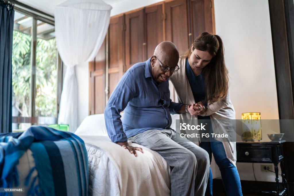 Heimpfleger hilft einem älteren Mann, der zu Hause aufsteht - Lizenzfrei Alter Erwachsener Stock-Foto