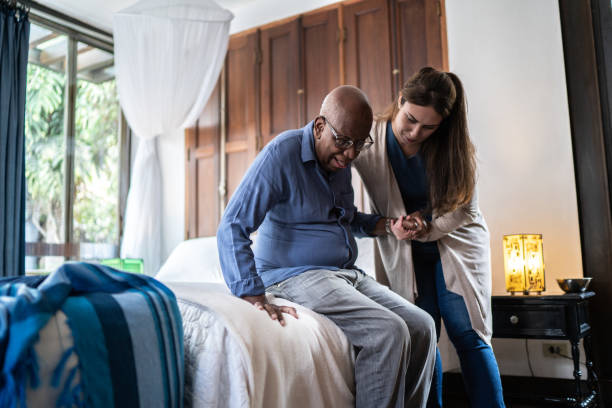 caregiver domestico che aiuta un uomo anziano in piedi a casa - personale sanitario foto e immagini stock