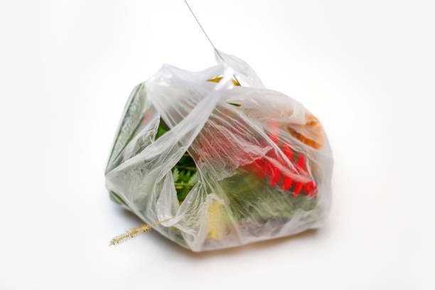 istock DEFOCUS. Save environmental. Red and green plants flowers in a plastic bag on a white background. A dry blade of grass sticks out. Ecological problems. Out of focus 1313009129