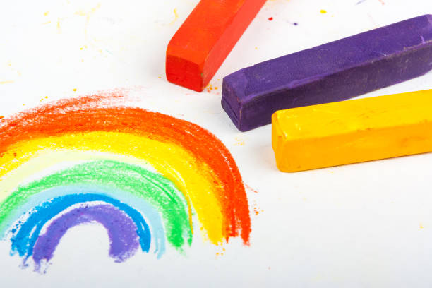 colorful rainbow drawing and crayons on white background stock photo
