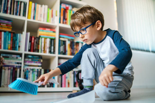 petit garçon caucasien quatre ans enfant balayant et nettoyant le plancher à la maison dans le travail domestique espiègle d’activité de loisir de jour et grandissant le concept réel de personnes - sweeping photos et images de collection