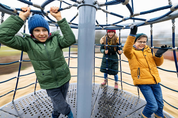 Kids playing on playground. Brothers and sister having fun on playground carousel. Rainy spring day.Nikon D850