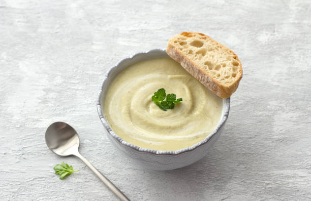 delicate creamy cauliflower soup with curry and coconut milk with fresh bread on light gray textured background - cauliflower vegetable portion cabbage imagens e fotografias de stock
