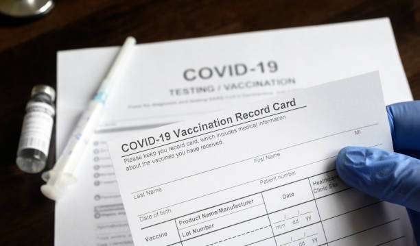 COVID-19 Vaccination Record Card in doctor hand COVID-19 Vaccination Record Card in doctor hand, coronavirus test and vaccine medical form on desk in clinic. Concept of corona virus vaccination certificate, health passport and immunization. occupational safety and health stock pictures, royalty-free photos & images