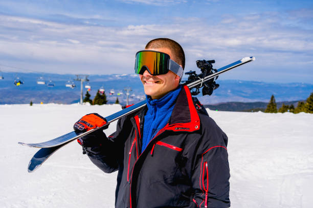 istock Smiling man with pair of skis in hands 1313024632