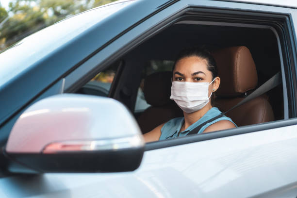 istock Young woman inside the car wearing protective mask 1313028293