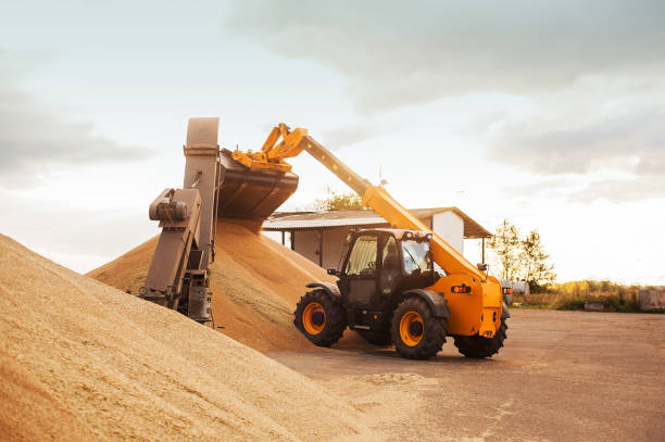 istock Grain elevator. Granary with mechanical equipment for receiving, cleaning, drying, grain shipment. Agricultural farm rural landscape. Grain Tractor makes dump silos 1313029751