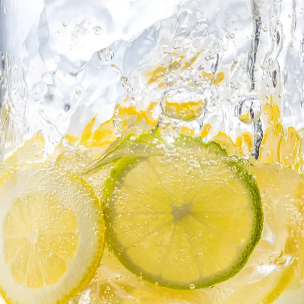 Photo of Cross section view on slices of lemon and lime in sparkling water.