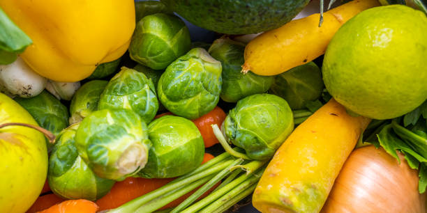 Close-up of green Brussels sprout buds with orange and yellow carrot.