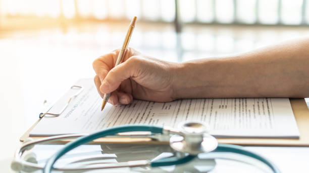 medical doctor writing on patient personal health care record discharge form, or prescription paperwork in hospital office, clinic center for healthcare and life insurance concept - note pad medicine healthcare and medicine pharmacy imagens e fotografias de stock