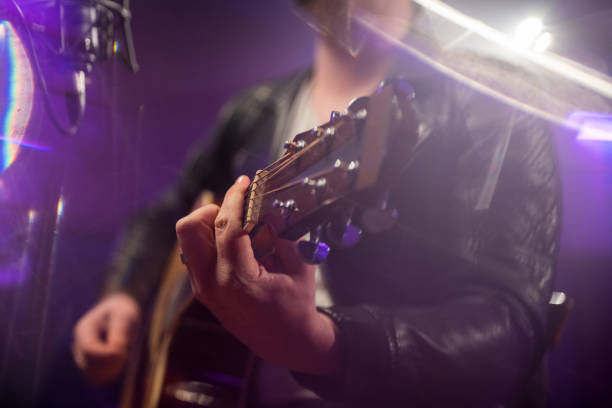 istock Rocker playing acoustic guitar in recording studio. Focused on hand pushing strings. 1313030706