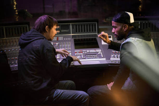 istock Two artists discussing their ideas while sitting at mixing console in recording studio. 1313030731