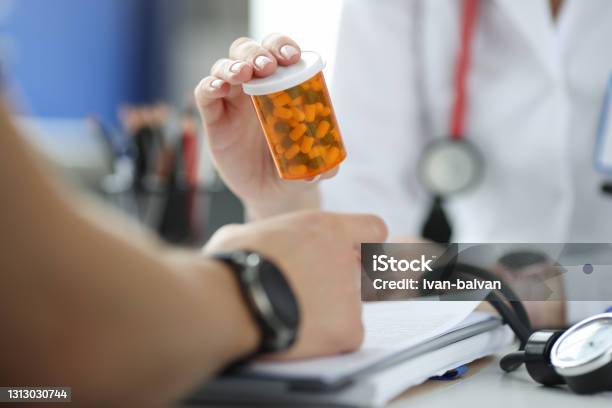 Doctor Holding Jar Of Medicines In Front Of Patient Closeup Stock Photo - Download Image Now