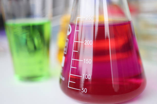 Close up of unrecognizable scientist taking laboratory flask with smoking purple liquid in laboratory.